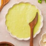 A bowl of poblano cream sauce with a wooden spoon.