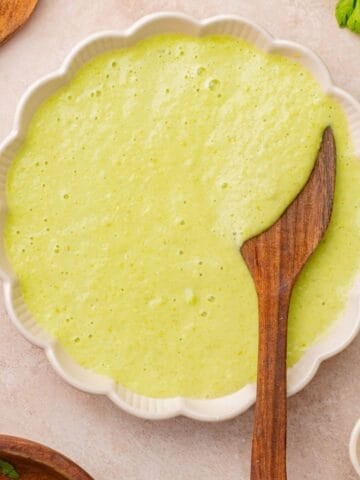 A bowl of poblano cream sauce with a wooden spoon.