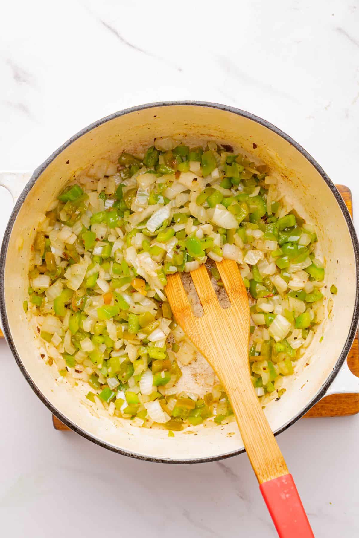 Chopped onions and peppers cooking in a Dutch oven.
