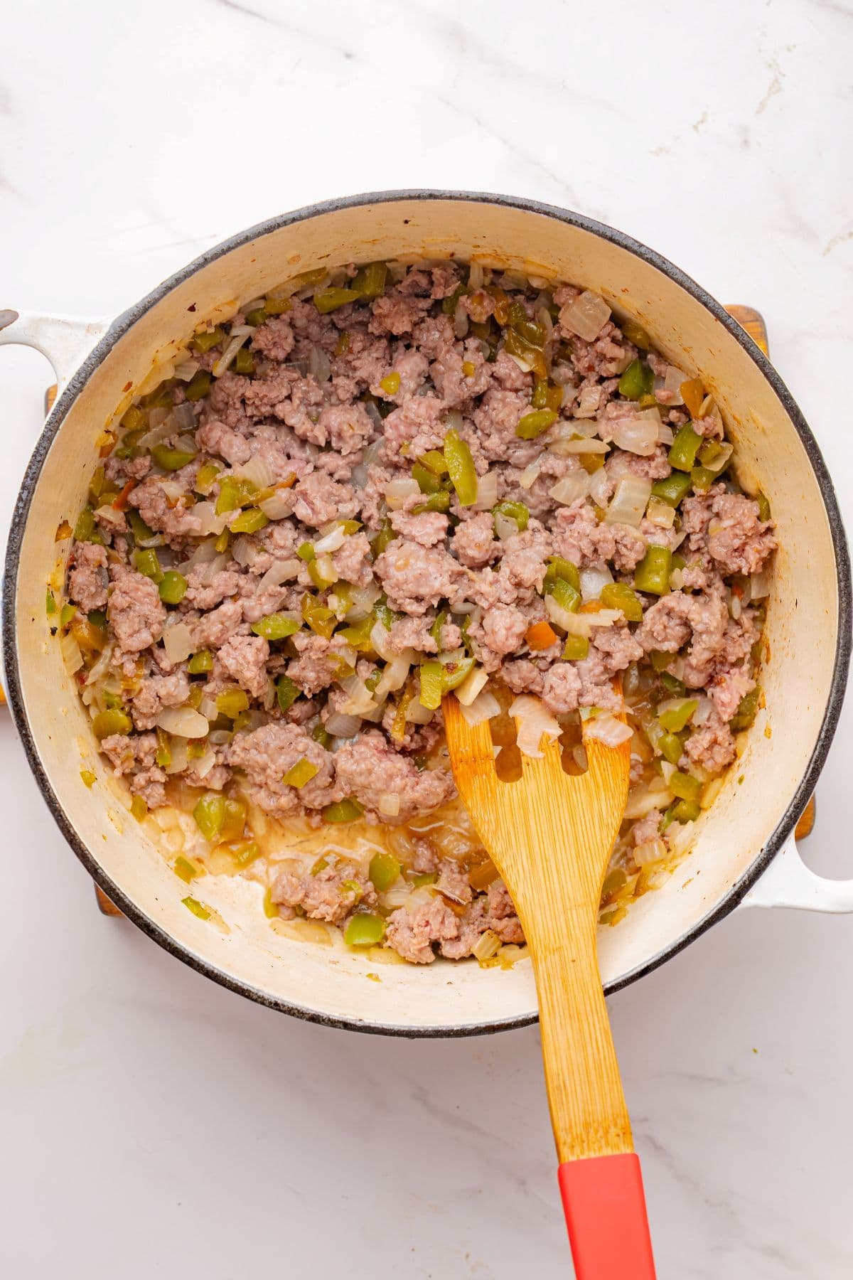 Ground beef browned in pot with vegetables.