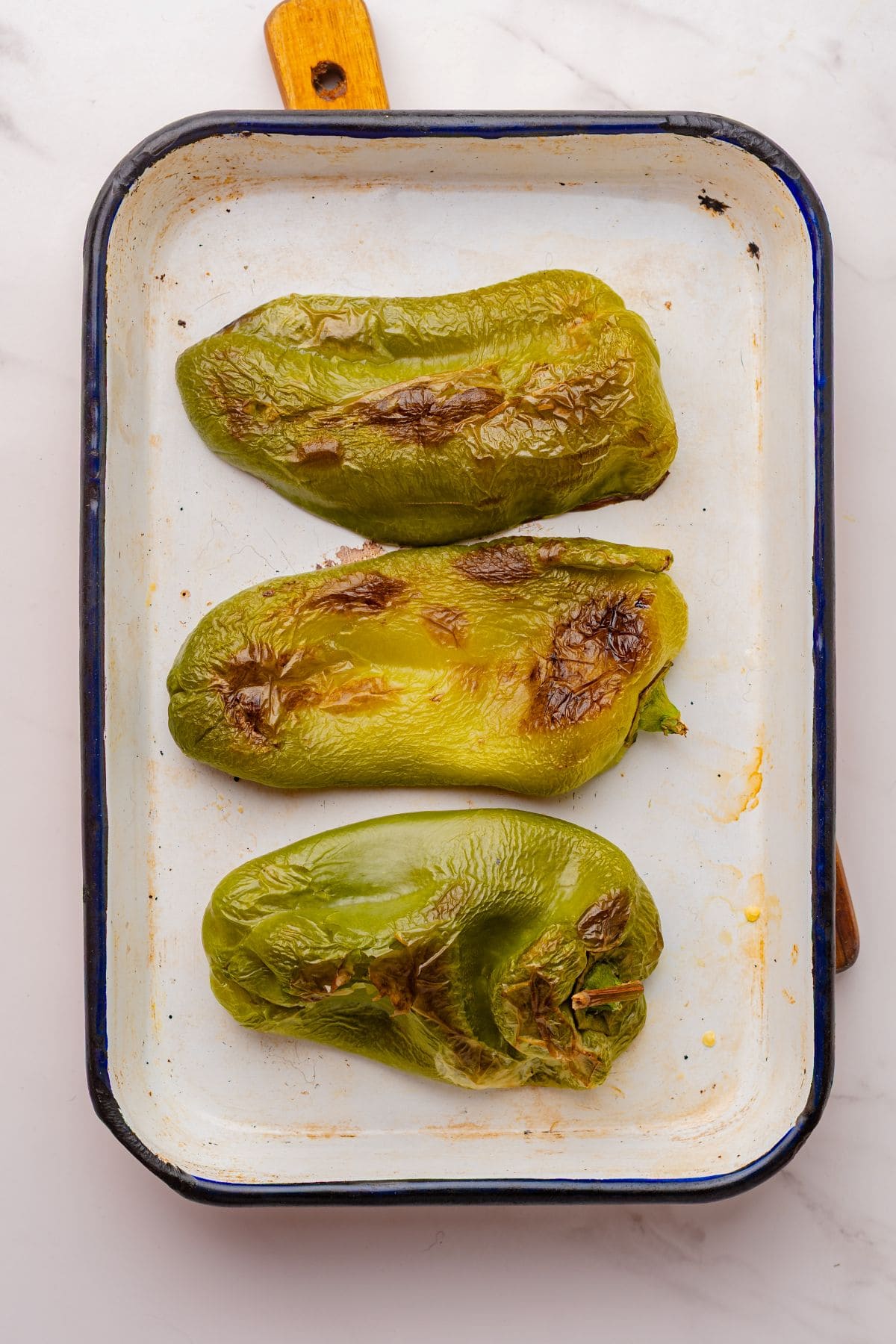 Roasted poblano peppers in a baking sheet.