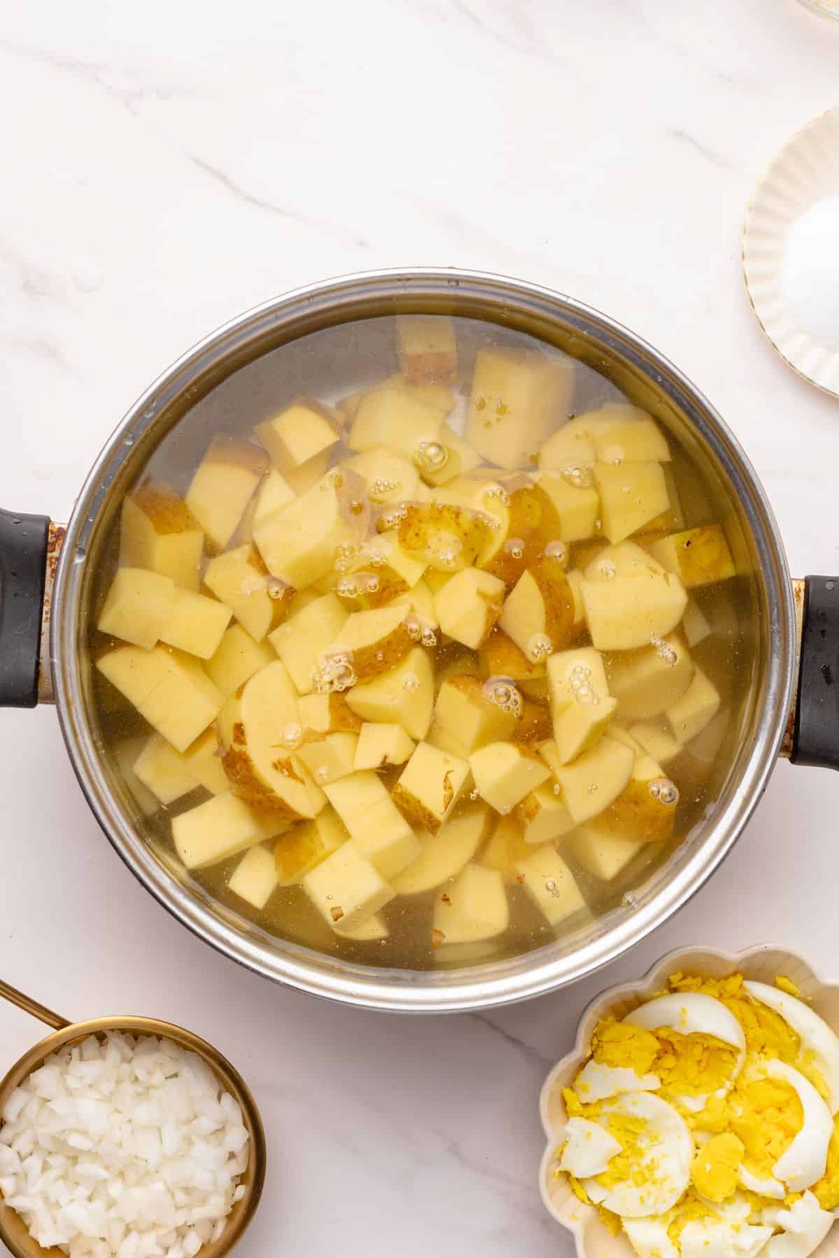 Potato cubes boiling in a pot of water.