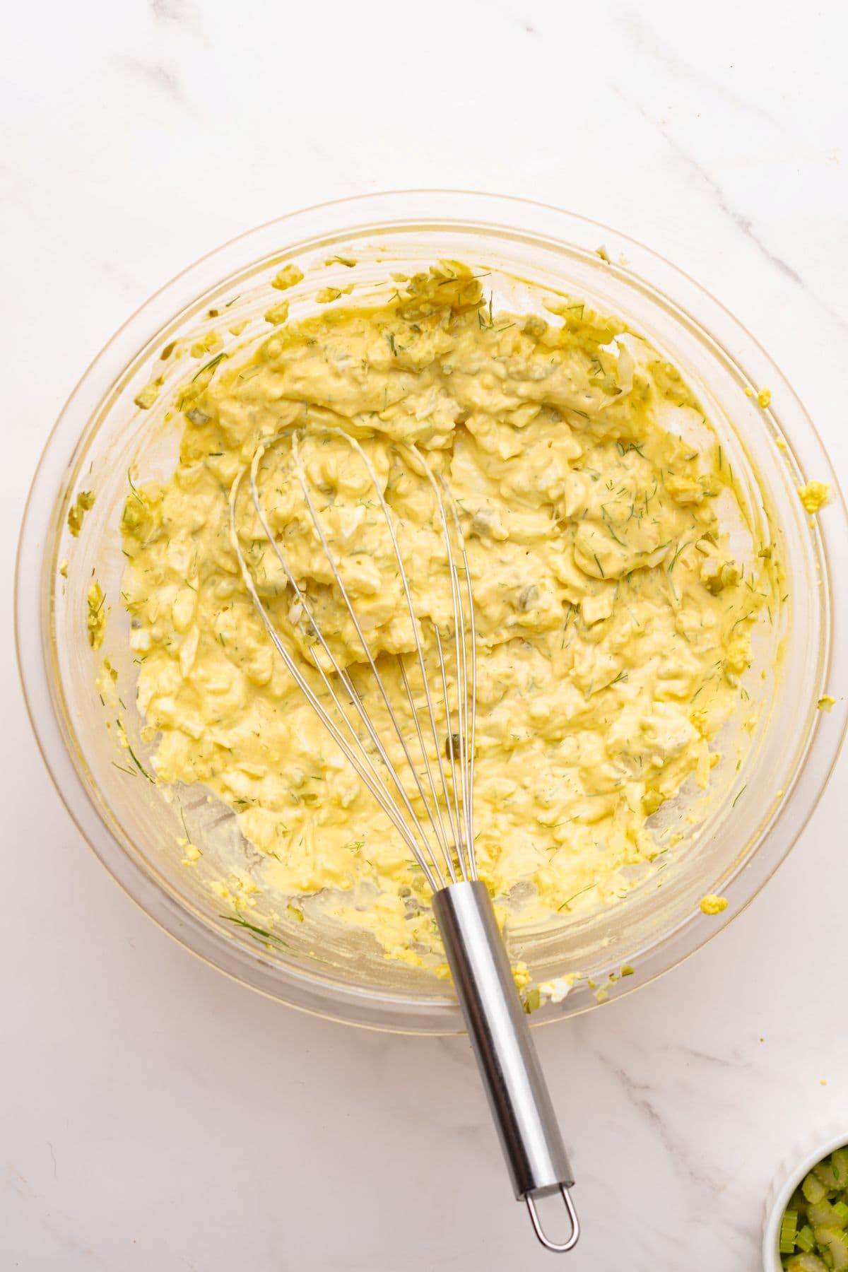 Potato salad dressing mixed in a bowl with a whisk.