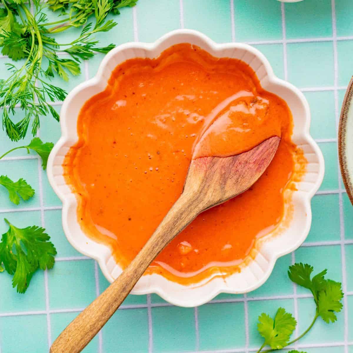 Small scalloped-edge bowl with an orange colored condiment in it.