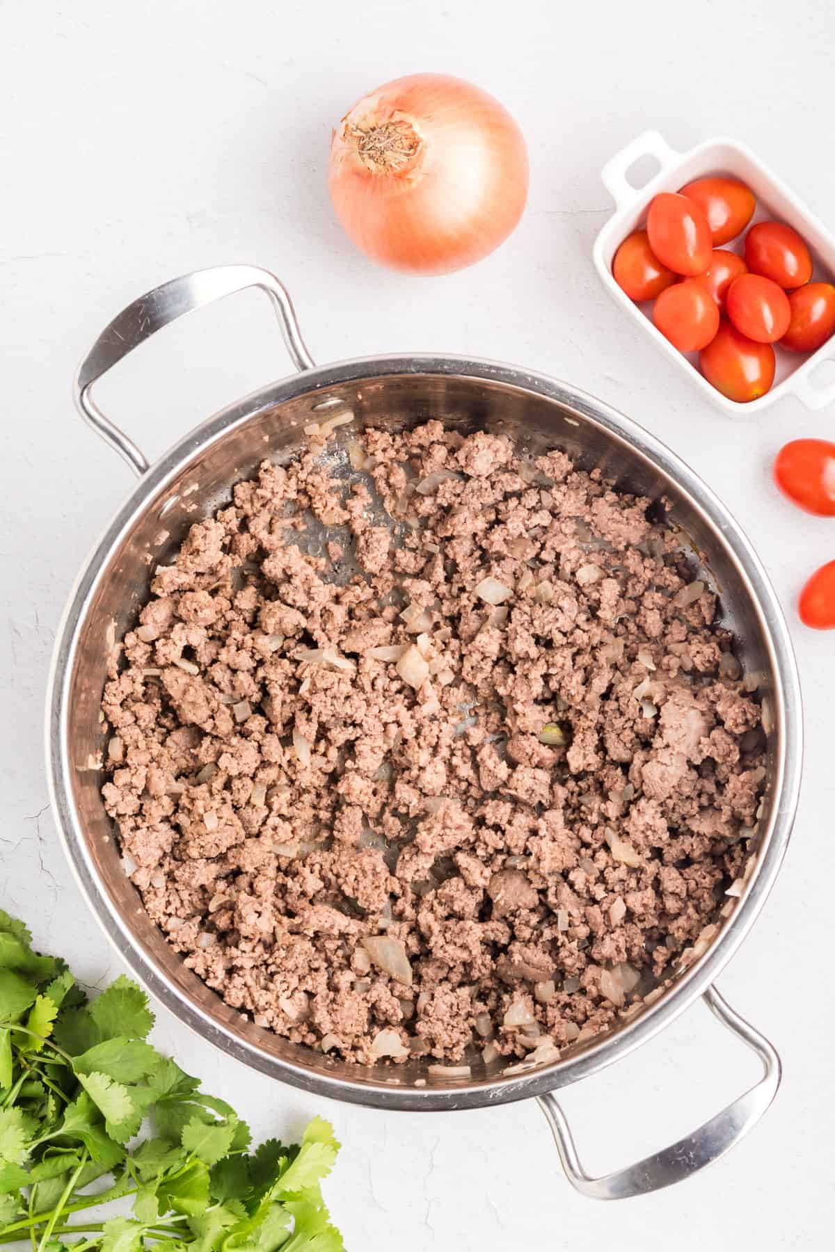 Ground beef and onions cooking in a skillet.