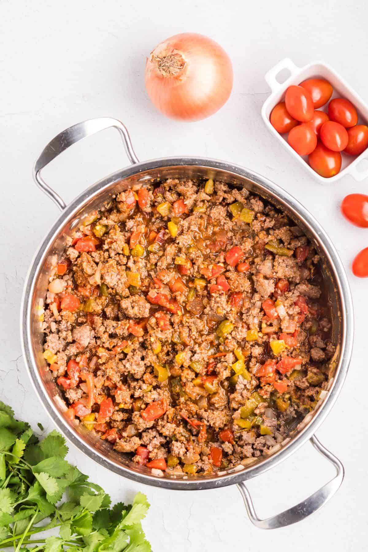 Ground beef with salsa, onions, and taco seasoning cooking in a skillet.
