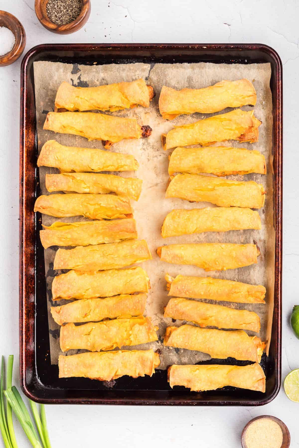 Baked chicken taquitos on a sheet pan.