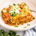 Slice of Mexican taco lasagna with tortillas and ground beef on a plate.