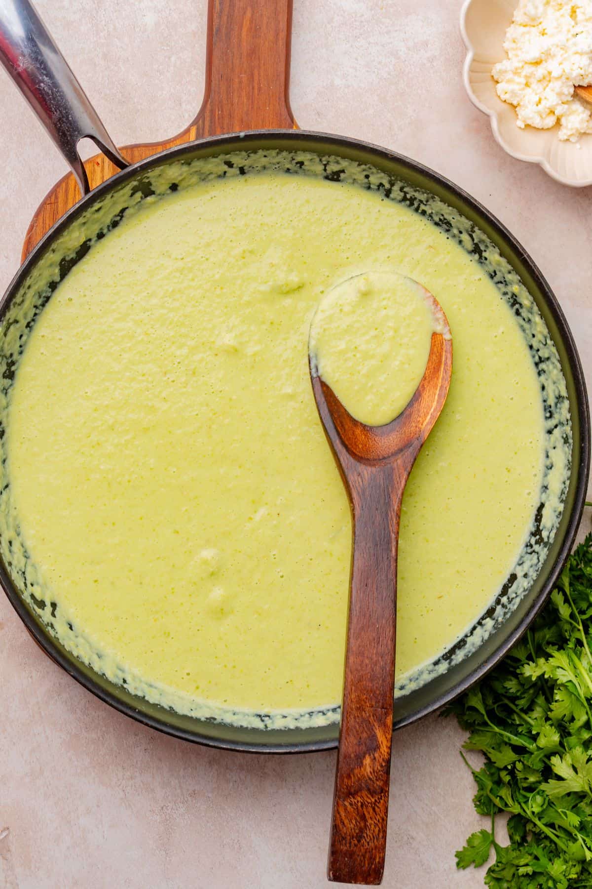 Creamy poblano sauce in a skillet with a wooden spoon.