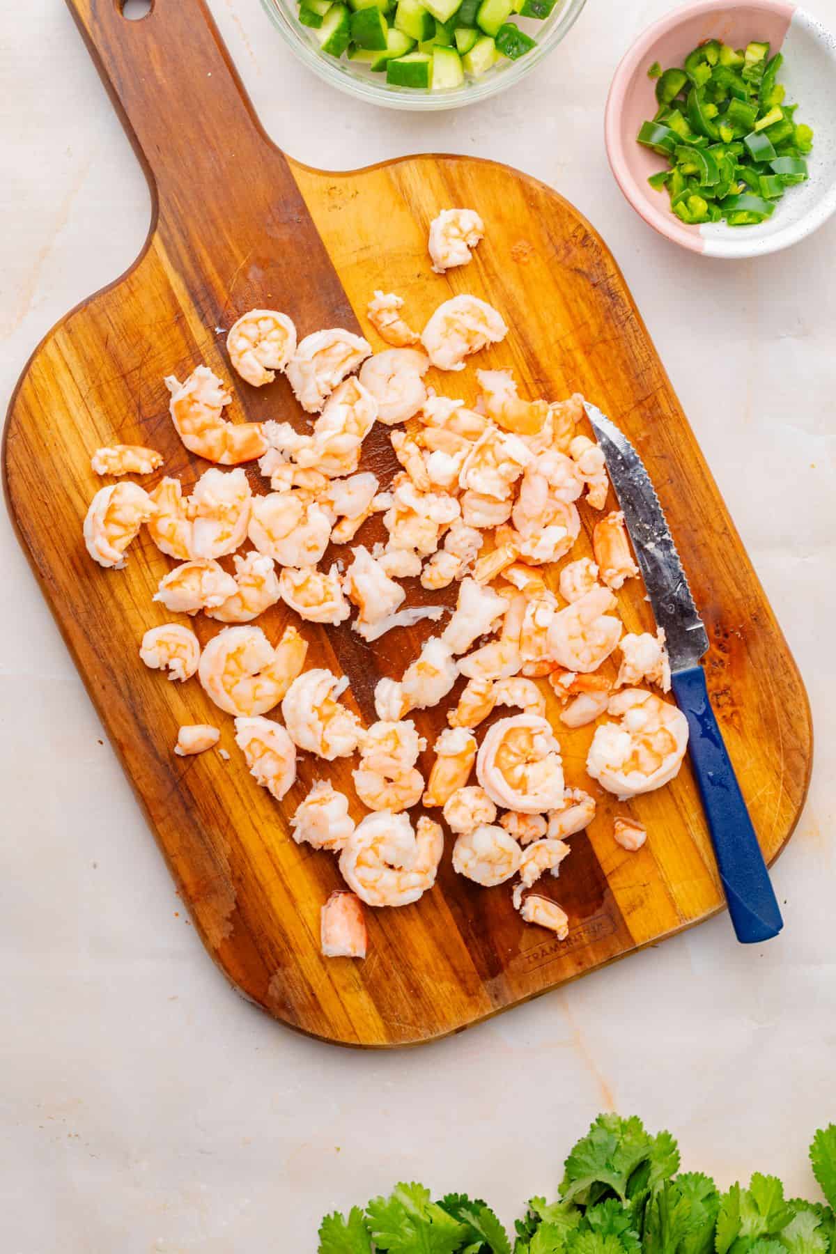 Chopped and poached shrimp on a cutting board.