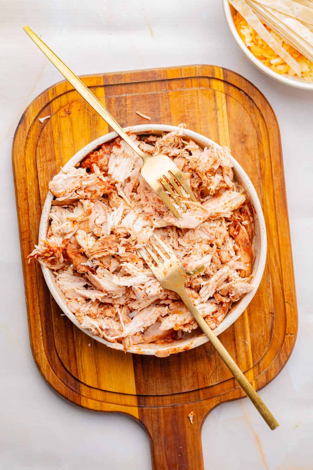 Shredded chicken in a bowl with two forks.