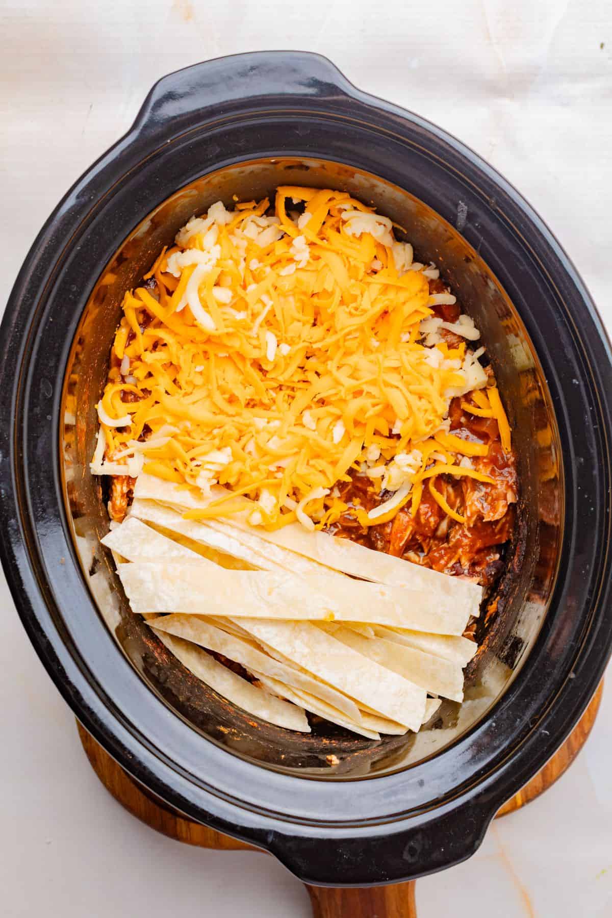 Cheese and corn tortillas added to the slow cooker.