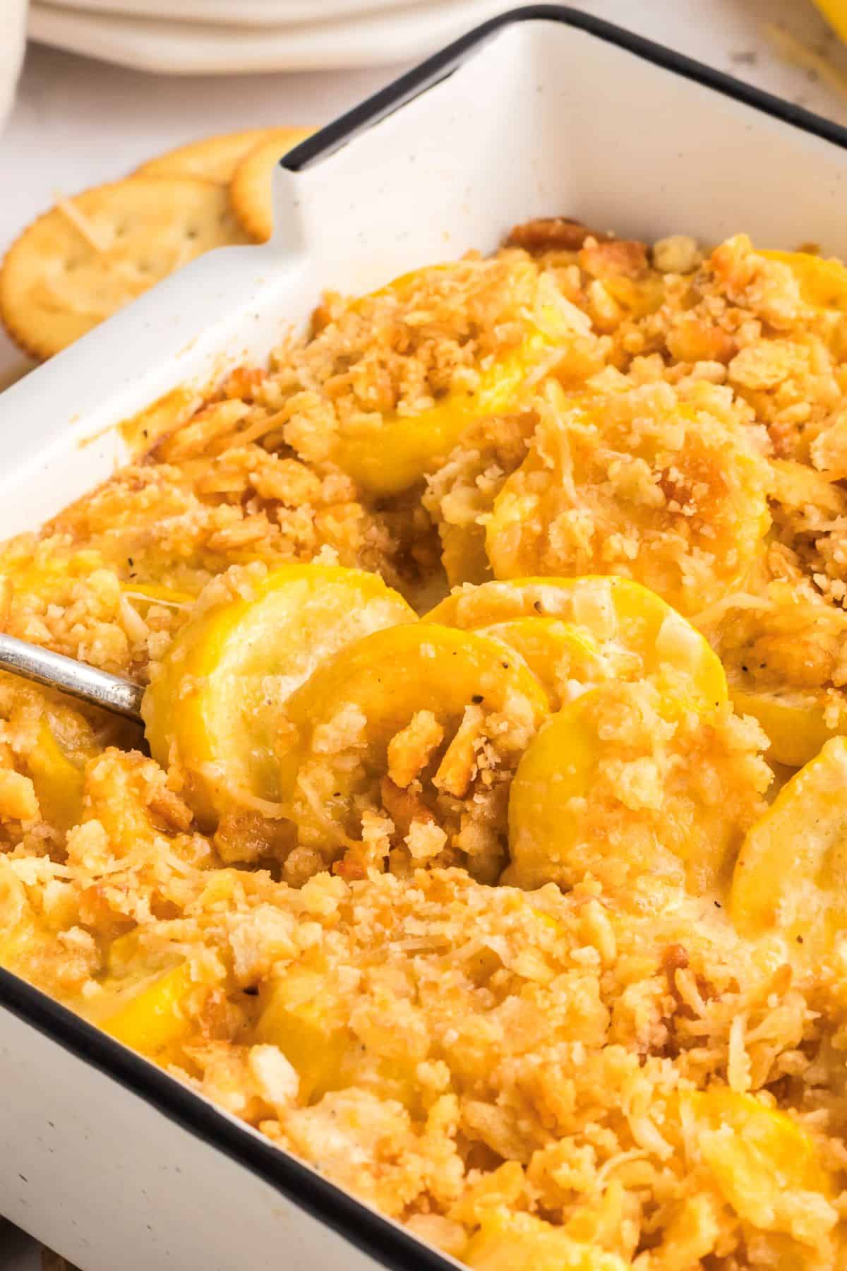 Southern squash casserole in a baking dish with a spoon.