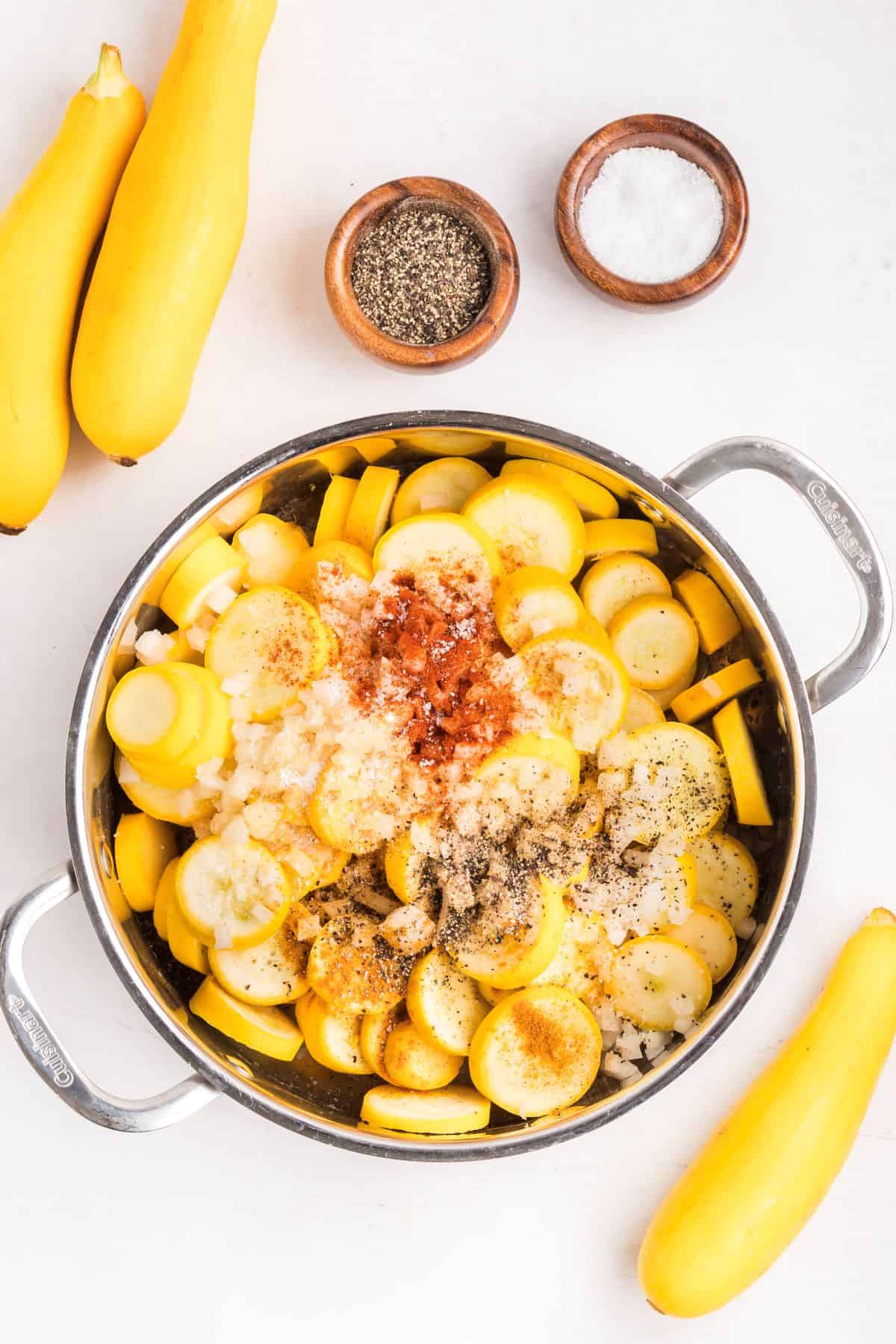 Sliced yellow squash, onions, and seasonings in a large skillet.